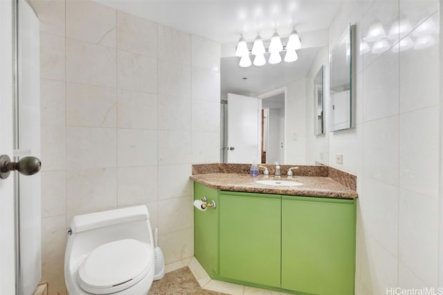 bathroom with toilet, vanity, tile walls, and tile patterned flooring