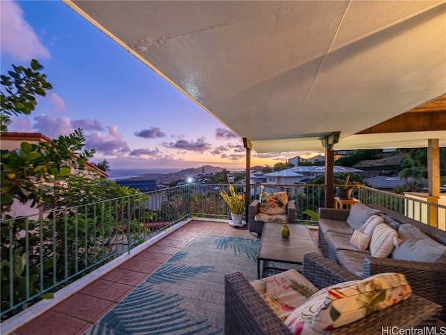 patio terrace at dusk with an outdoor living space and a balcony