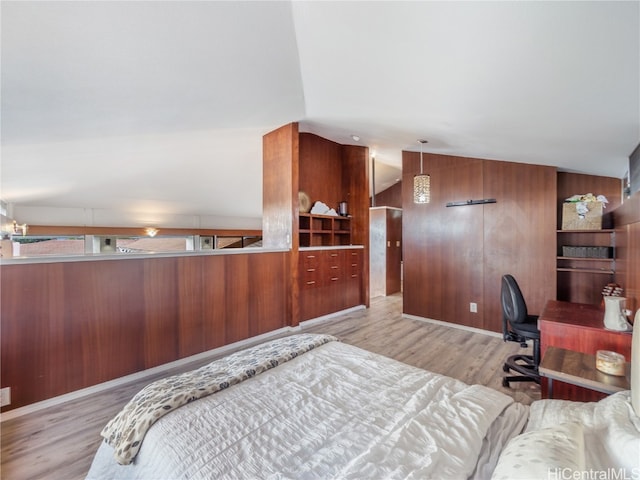 bedroom featuring wood walls, light hardwood / wood-style floors, and lofted ceiling