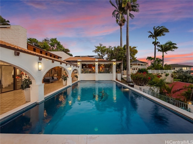 pool at dusk featuring a patio area