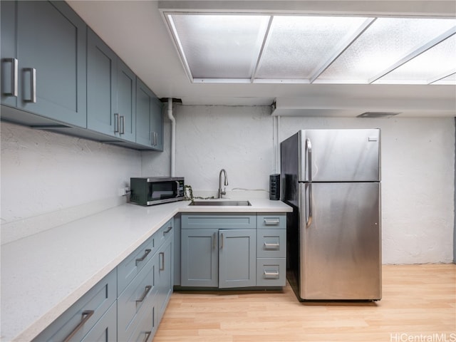 kitchen with sink, stainless steel appliances, and light hardwood / wood-style floors