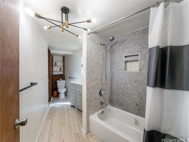 full bathroom featuring shower / bath combo, vanity, wood-type flooring, a notable chandelier, and toilet