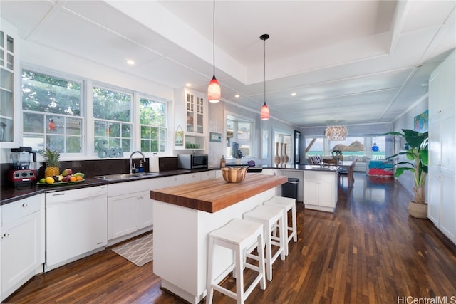 kitchen featuring dark hardwood / wood-style flooring, a kitchen island, white cabinetry, white dishwasher, and sink