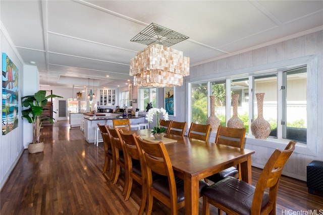 dining area with a notable chandelier, ornamental molding, and dark hardwood / wood-style flooring