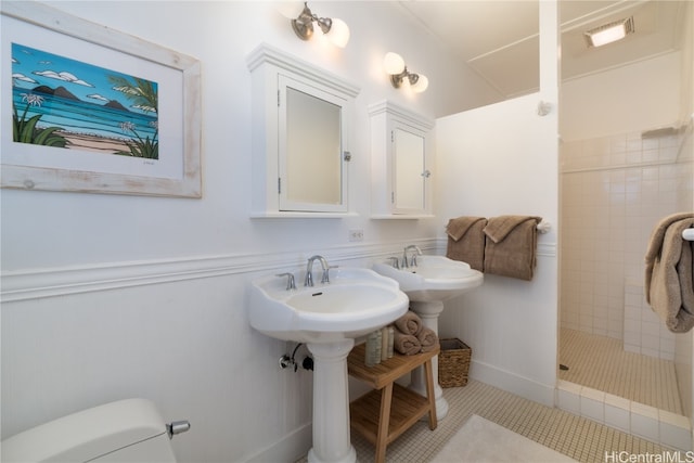 bathroom featuring toilet, tile patterned floors, and tiled shower