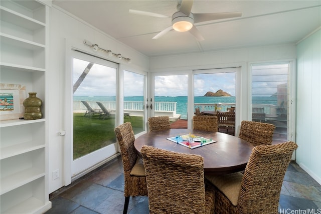 sunroom featuring a water view and ceiling fan