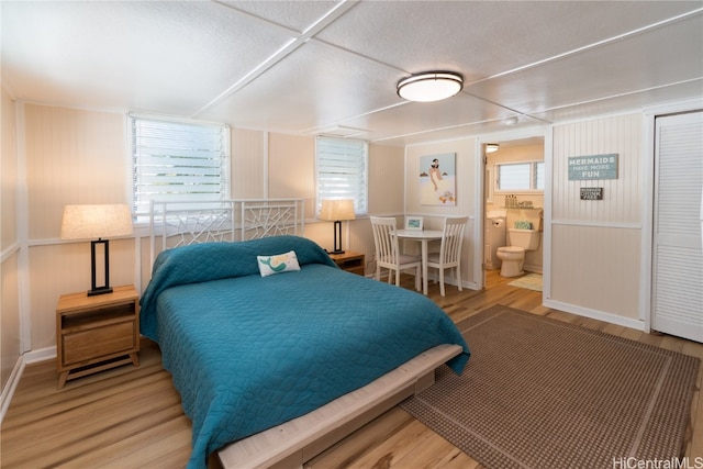 bedroom with ensuite bathroom and light wood-type flooring