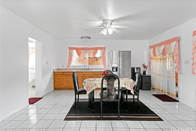 tiled dining area with ceiling fan and sink