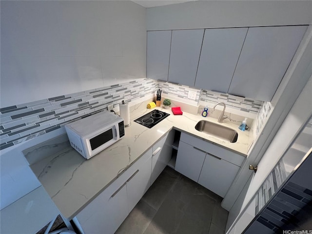 2463 Kuhio Ave Unit 405, Honolulu, HI 96815 - kitchen with white microwave, a sink, black electric cooktop, backsplash, and modern cabinets
