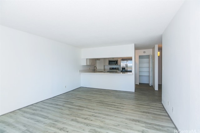 unfurnished living room featuring sink and light hardwood / wood-style floors