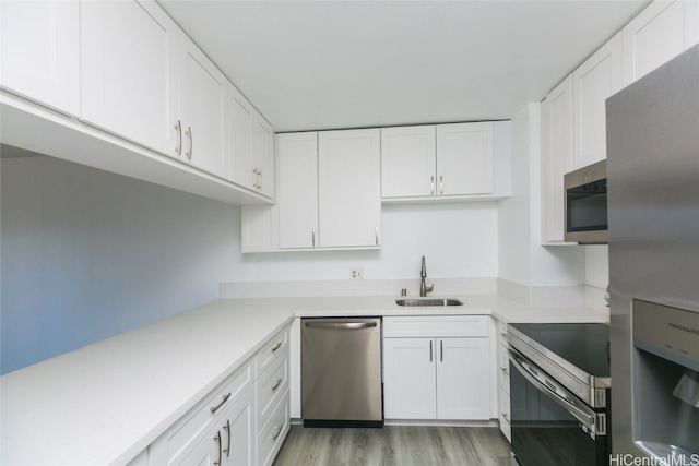 kitchen with light hardwood / wood-style flooring, stainless steel appliances, sink, and white cabinets