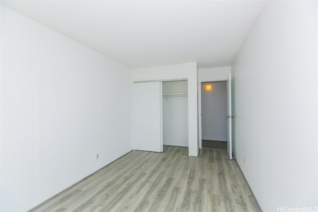 unfurnished bedroom with a closet and light wood-type flooring