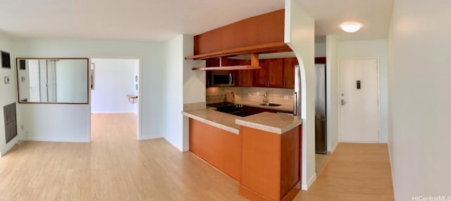 kitchen featuring tasteful backsplash, sink, light hardwood / wood-style flooring, and appliances with stainless steel finishes