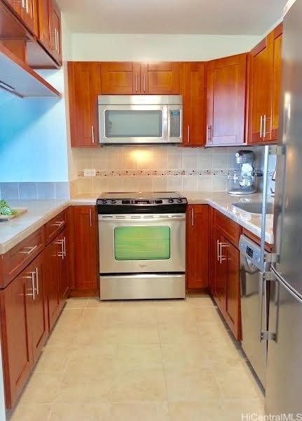 1925 Kalakaua Ave Unit 1902, Honolulu, HI 96815 - kitchen featuring brown cabinetry, appliances with stainless steel finishes, light countertops, and decorative backsplash