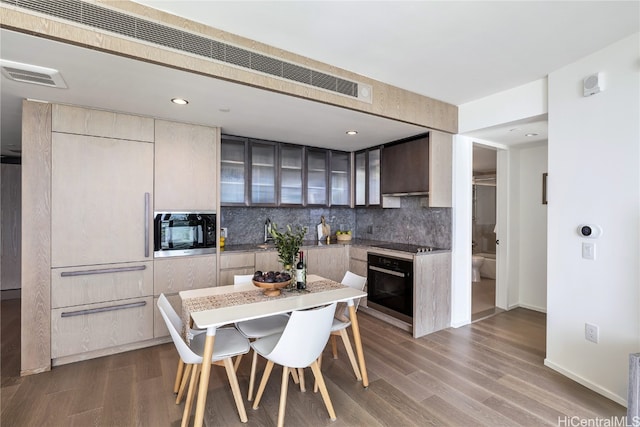 kitchen with tasteful backsplash, oven, stainless steel microwave, wood-type flooring, and a kitchen island