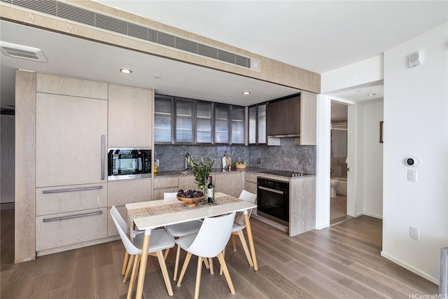kitchen featuring visible vents, backsplash, glass insert cabinets, wood finished floors, and black appliances