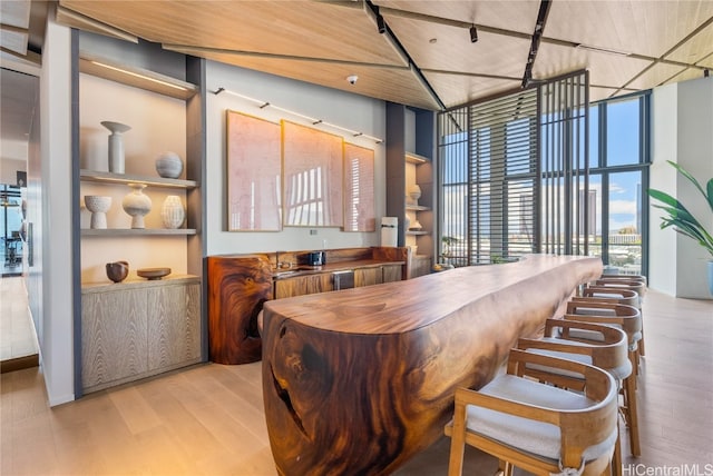 dining area with light hardwood / wood-style floors, floor to ceiling windows, and a towering ceiling