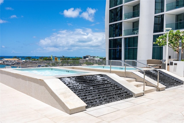 community pool with a patio area and fence