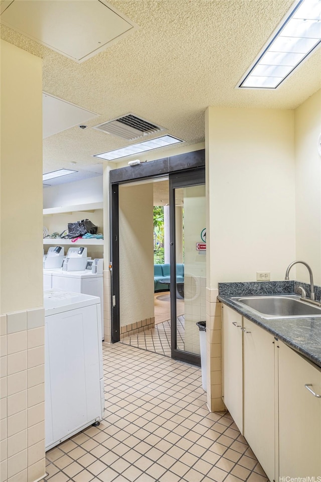 interior space with visible vents, dark countertops, a textured ceiling, a sink, and independent washer and dryer