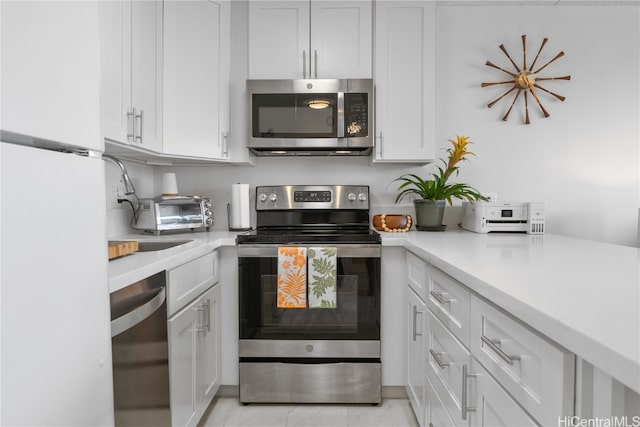 kitchen with appliances with stainless steel finishes, white cabinets, and light tile patterned flooring