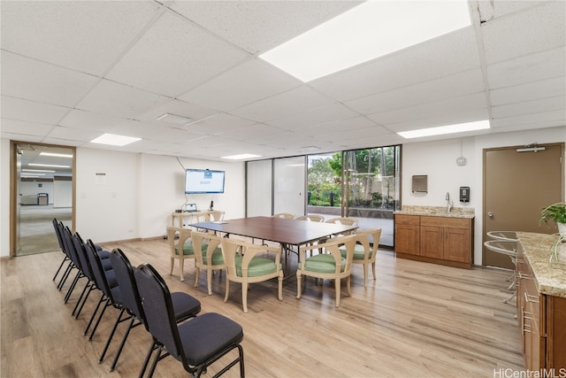 dining area featuring light hardwood / wood-style floors, a paneled ceiling, and sink