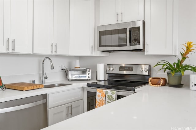 kitchen with sink, appliances with stainless steel finishes, and white cabinetry