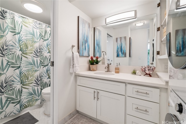 bathroom featuring vanity, washer / clothes dryer, and toilet