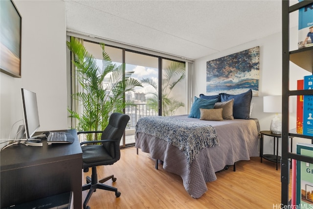 bedroom featuring expansive windows, hardwood / wood-style floors, and a textured ceiling