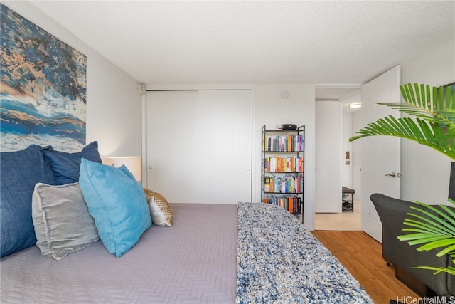 bedroom with a closet, light hardwood / wood-style floors, and a textured ceiling