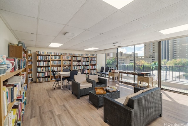 living room featuring a drop ceiling, light hardwood / wood-style flooring, and floor to ceiling windows