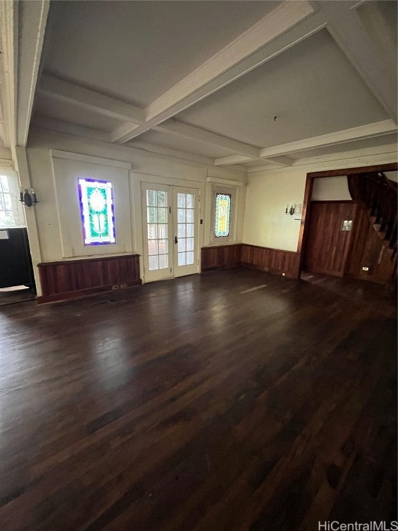 unfurnished living room with wooden walls, dark hardwood / wood-style flooring, beamed ceiling, and french doors