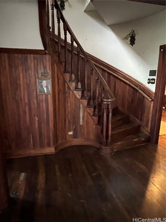 stairway featuring hardwood / wood-style floors and wooden walls