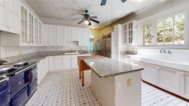 kitchen featuring white cabinets, a kitchen island, ornamental molding, and sink