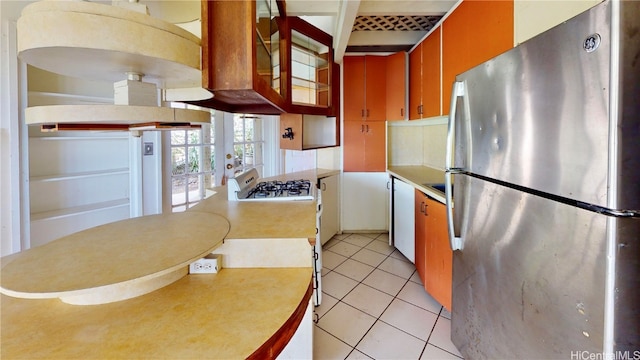 kitchen with white gas stove, stainless steel fridge, light tile patterned flooring, and french doors