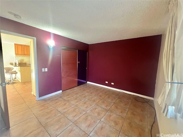 unfurnished bedroom featuring a closet, light tile patterned floors, and a textured ceiling