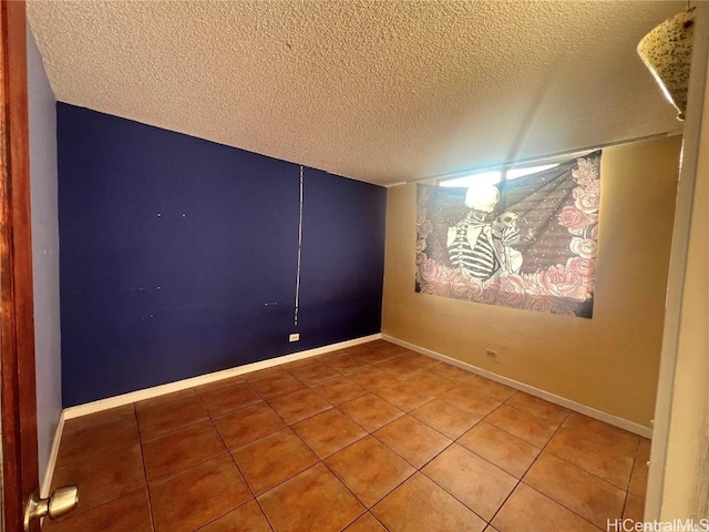 tiled empty room featuring a textured ceiling