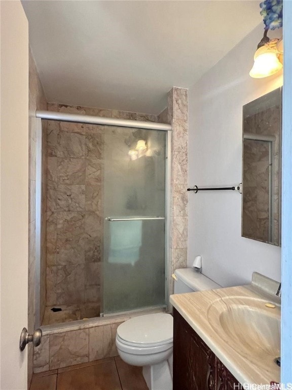 bathroom featuring tile patterned flooring, vanity, toilet, and a shower with door