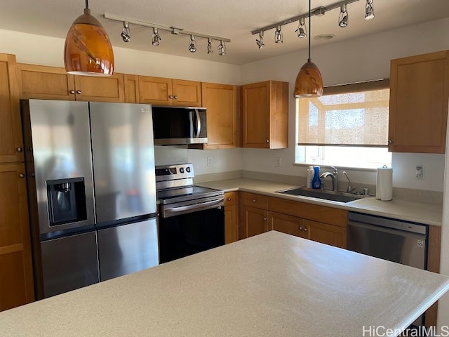 kitchen with track lighting, stainless steel appliances, sink, and pendant lighting