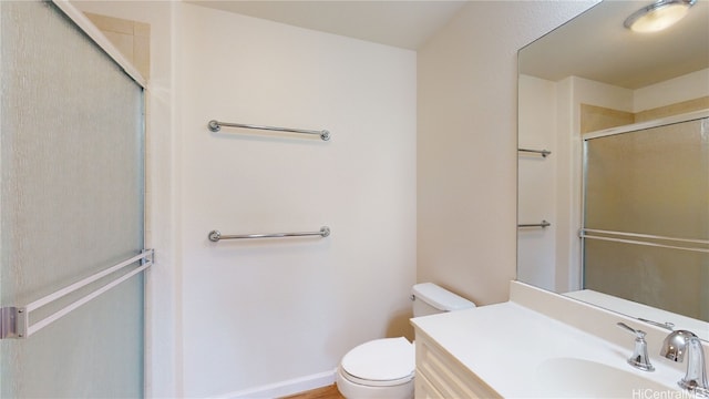 bathroom featuring toilet, a shower with shower door, and vanity