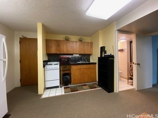 kitchen featuring white appliances, sink, decorative backsplash, a textured ceiling, and light colored carpet