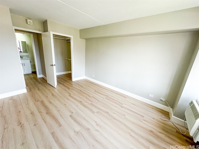 unfurnished bedroom with a closet, light hardwood / wood-style flooring, and a wall unit AC