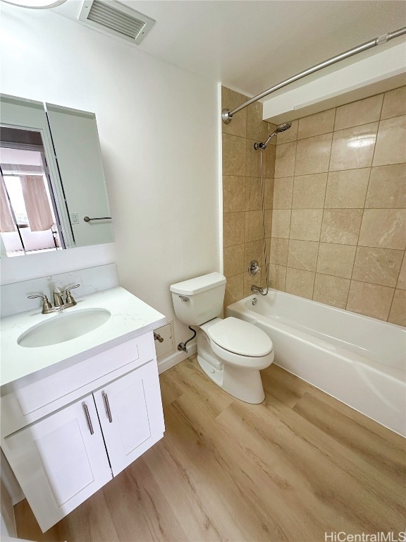 full bathroom with vanity, toilet, tiled shower / bath, and hardwood / wood-style floors