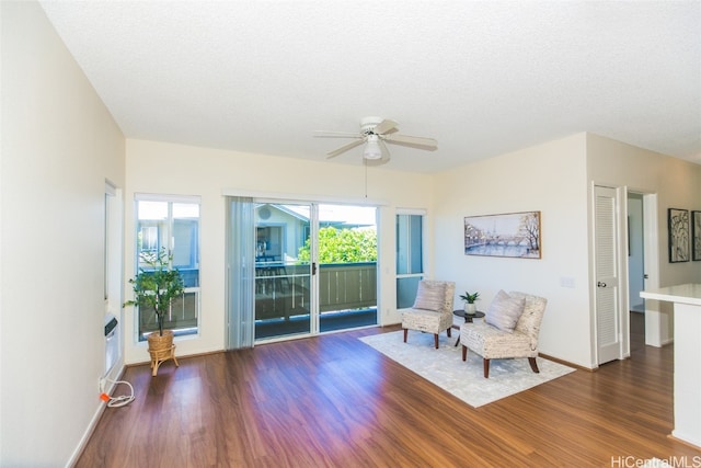 living area featuring dark wood-type flooring, a textured ceiling, and ceiling fan