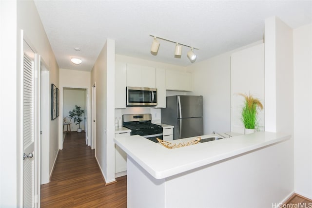 kitchen with dark wood-type flooring, appliances with stainless steel finishes, kitchen peninsula, and white cabinets