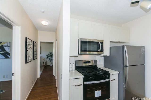 kitchen featuring white cabinetry, stainless steel appliances, a textured ceiling, and dark hardwood / wood-style floors