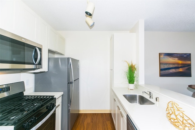 kitchen featuring dark hardwood / wood-style flooring, appliances with stainless steel finishes, a textured ceiling, white cabinetry, and sink