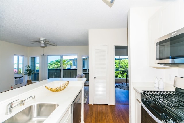 kitchen featuring appliances with stainless steel finishes, sink, a textured ceiling, dark hardwood / wood-style flooring, and white cabinetry