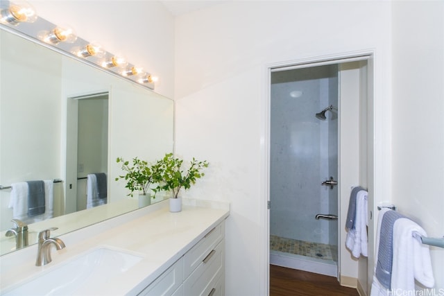 bathroom with vanity, tiled shower, and wood-type flooring