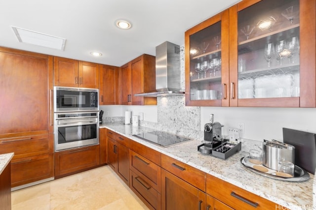 kitchen featuring light stone counters, wall chimney exhaust hood, appliances with stainless steel finishes, and tasteful backsplash