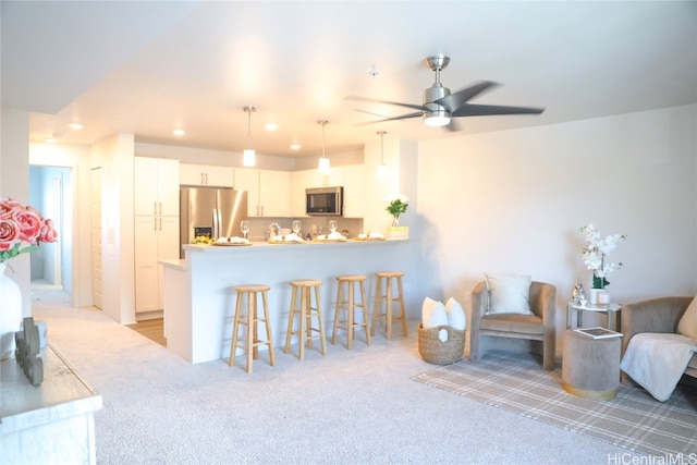 interior space with kitchen peninsula, a kitchen breakfast bar, white cabinetry, stainless steel appliances, and pendant lighting